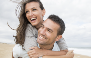 man carrying woman on his back on beach