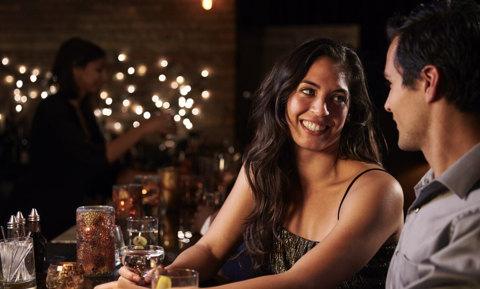 girl and guy at a bar, there's another girl in backgrounded out of focus.