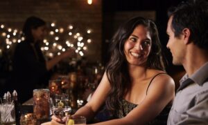 girl and guy at a bar, there's another girl in backgrounded out of focus.