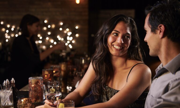 girl and guy at a bar, there's another girl in backgrounded out of focus.