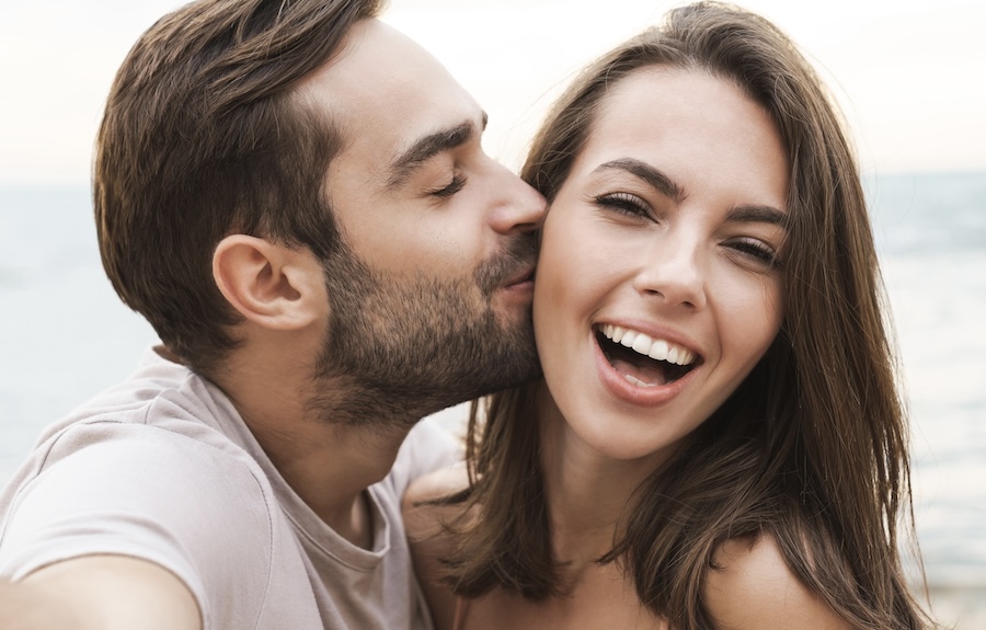 couple smiling as man kisses her on cheek