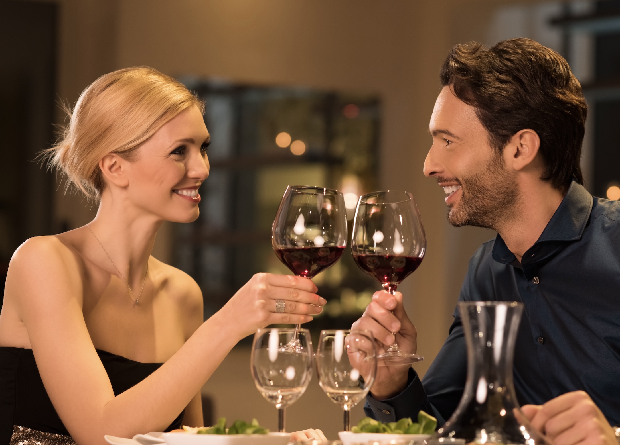 couple at dinner wearing formal attire drinking red wine