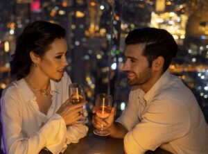 couple on date at night, sharing wine, overlooking a major city