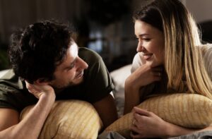 couple talking and smiling while laying on throw pillows
