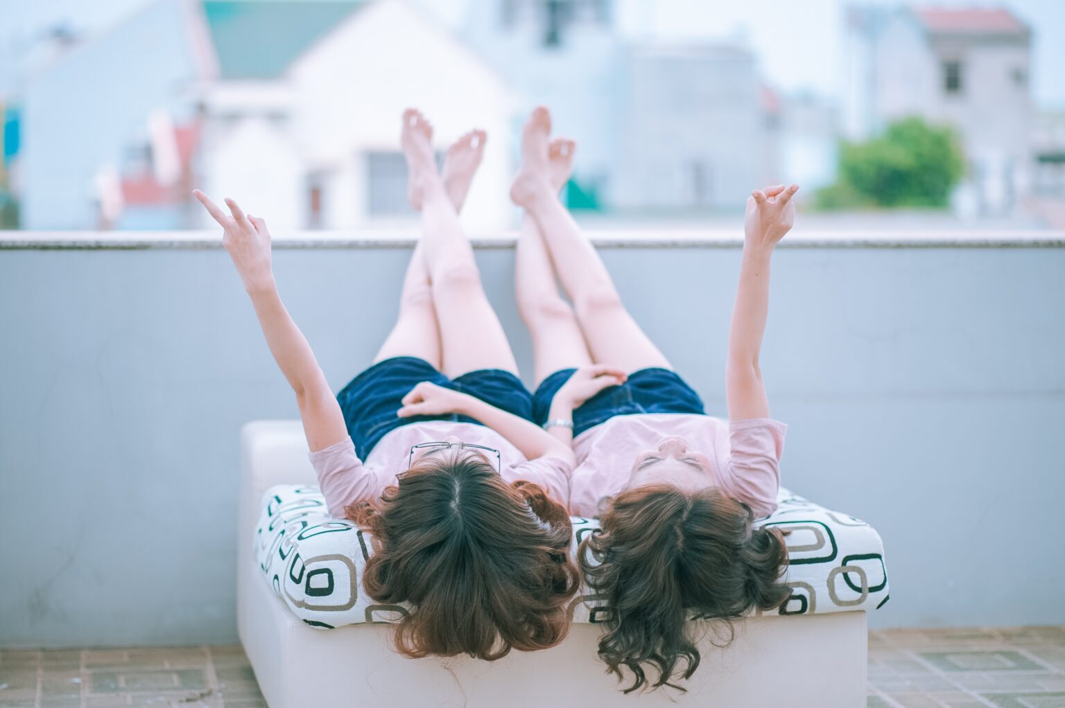 Two girls lying and laughing because they are Lesbian swingers UK