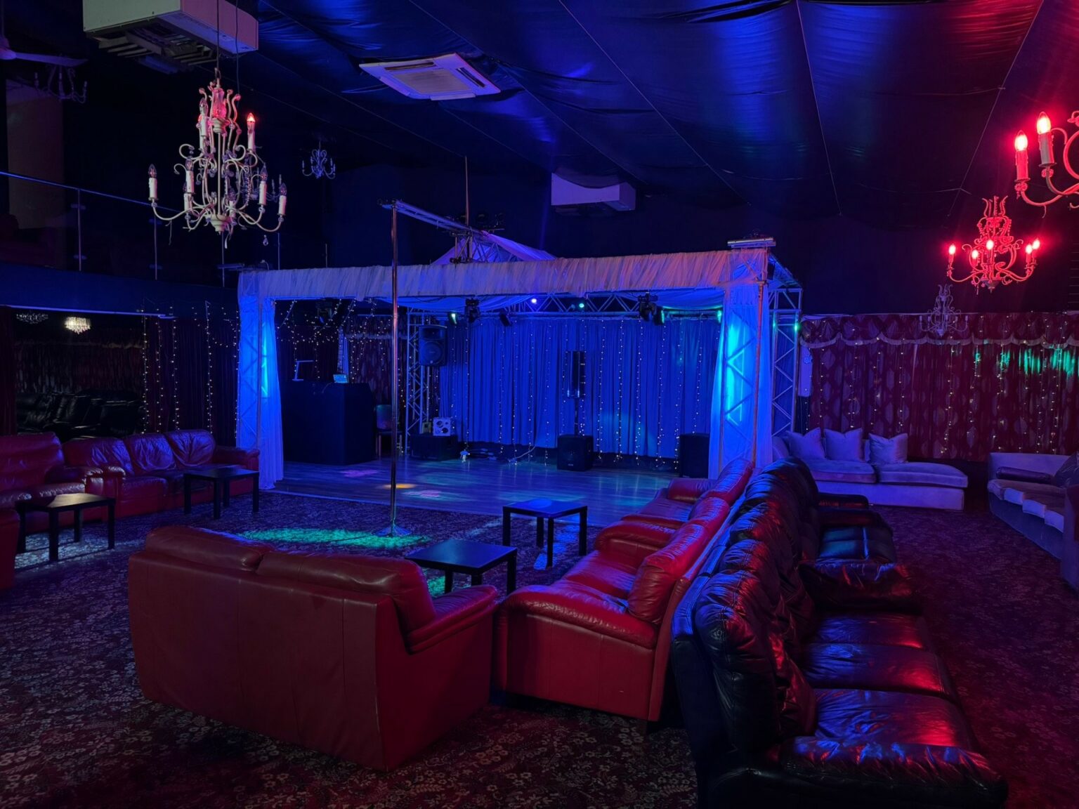 Interior of the club Pandora in Leeds, Armley, showing red leather sofas, stage with lights, dancing pole and dancing floor